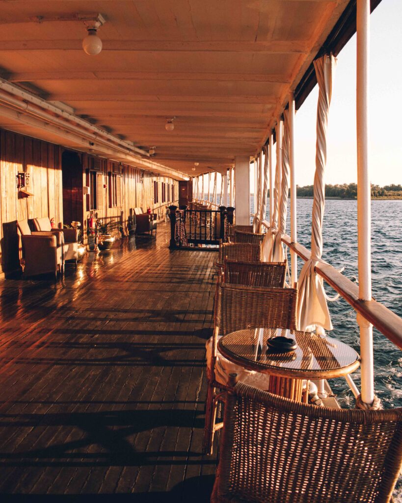 Golden afternoon sunlight over a wooden boat deck with wicker chairs on a Nile Cruise