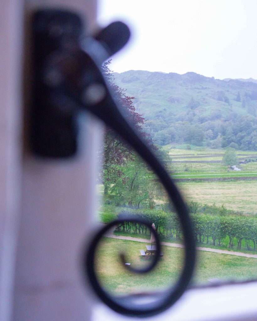 Green hills of Lake District on a rainy day seen past a black window catch