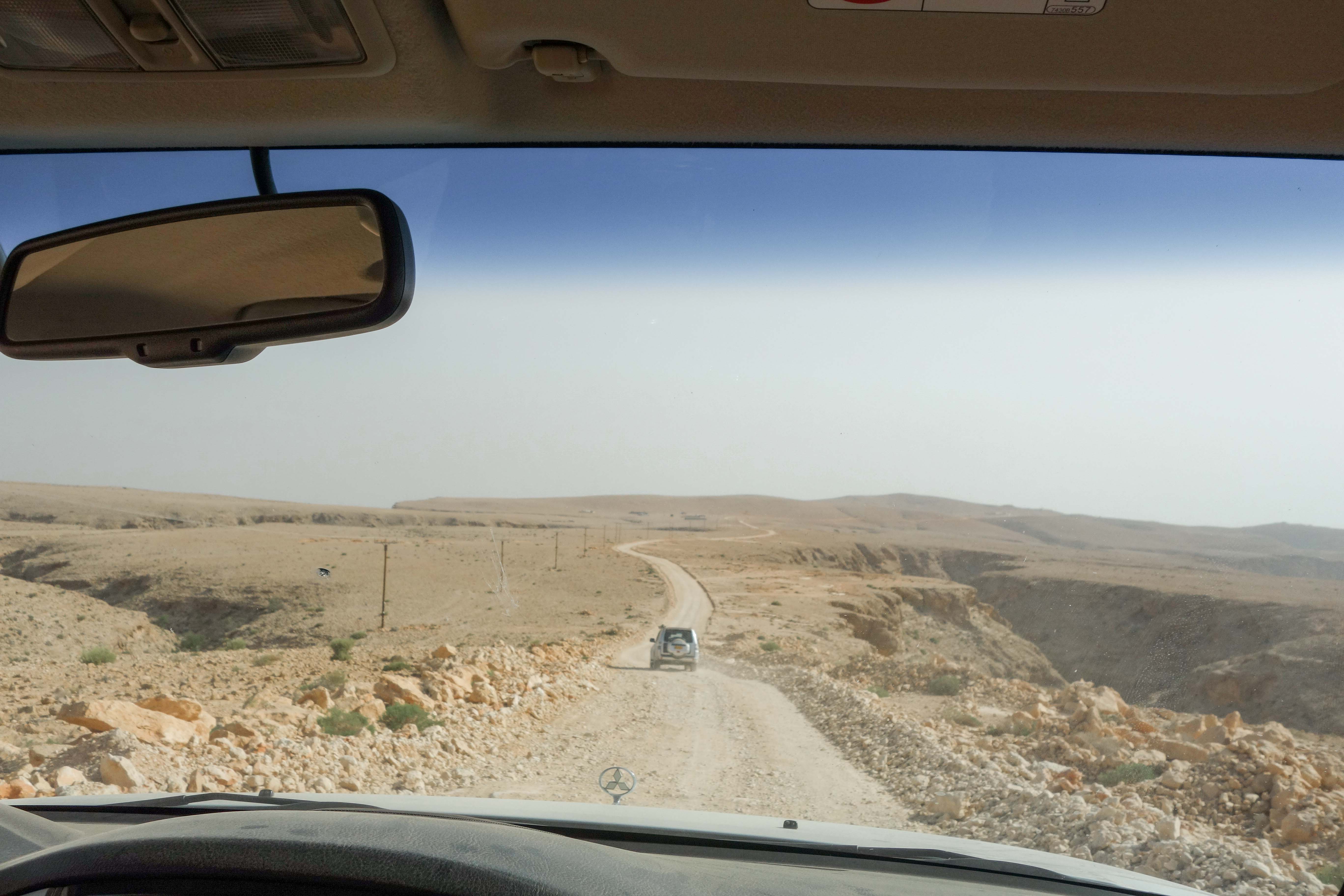 View through vehicle windscreen of a 4WD car driving along off road track on top of Salma Plateau, Oman