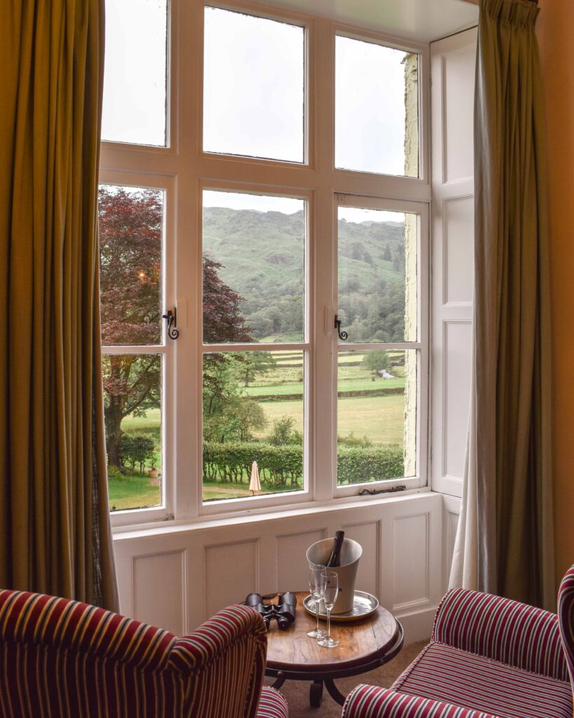 View out over Lake District fells from large bay window with two red striped armchairs