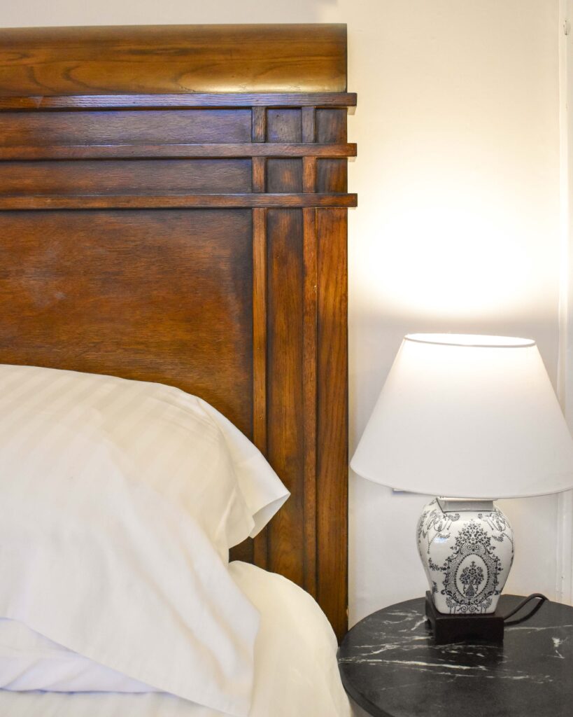 Close up of wooden headboard, white pillows and bedside lamp at Lancrigg Hotel