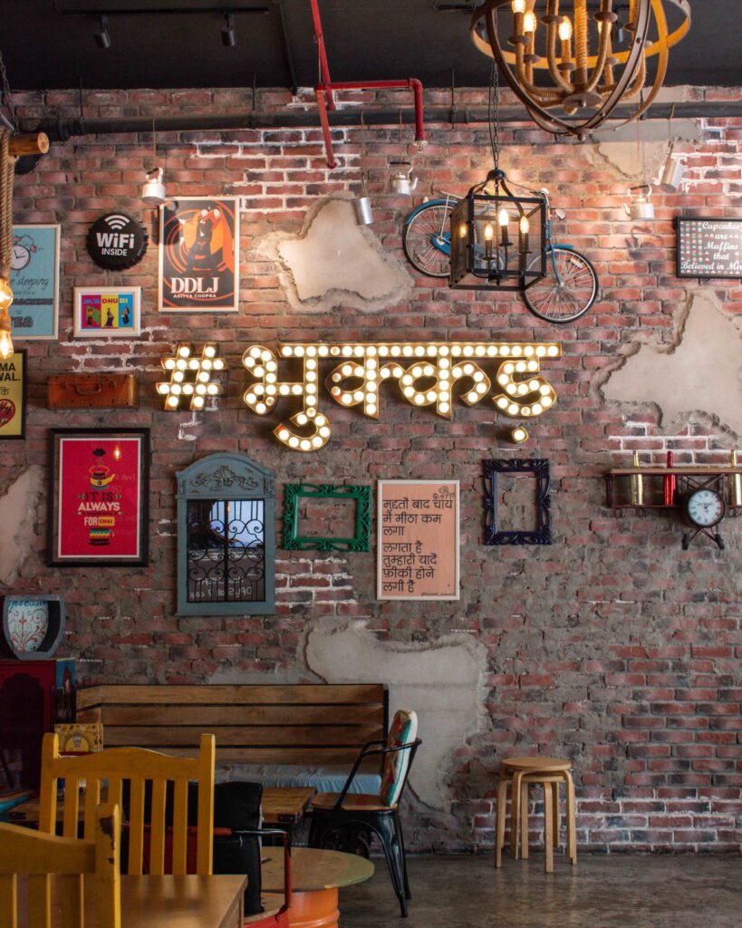 Brick wall with eclectic art work and Hindi light up sign at Bhukkad Cafe, Dubai