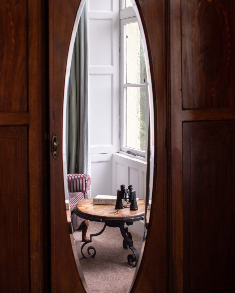 Reflection in wardrobe mirror of small table with binoculars 