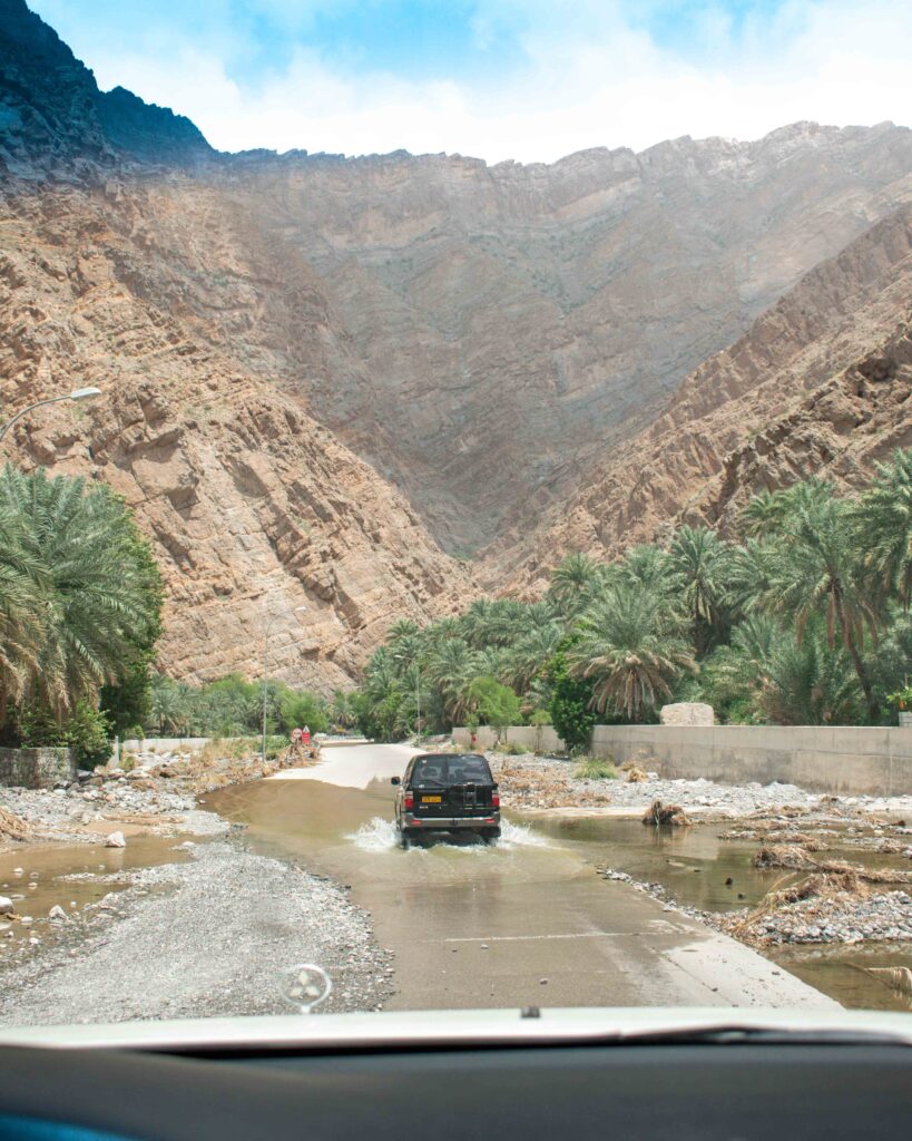 Car driving through water on track in Wadi Bani Awf, Oman