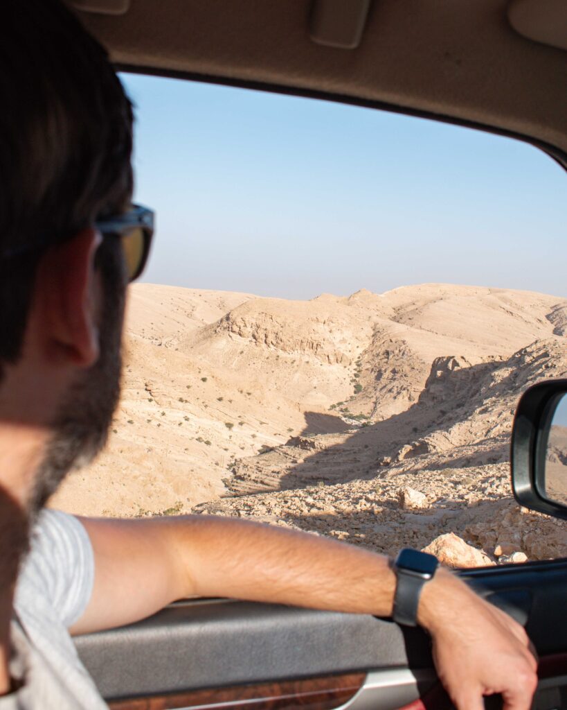 Man looking out of car window over Salma Plateau, Oman
