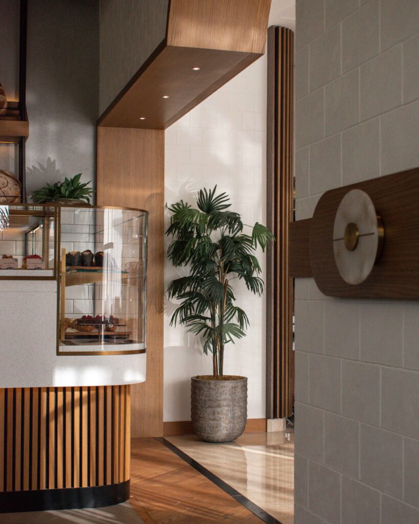 Green pot plant in front of white tiled and wooden pastry counter at Risen Dubai