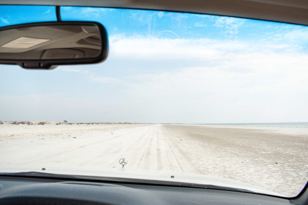 Windscreen view driving off road track along Al Khaluf beach, Sugar Dunes, Oman