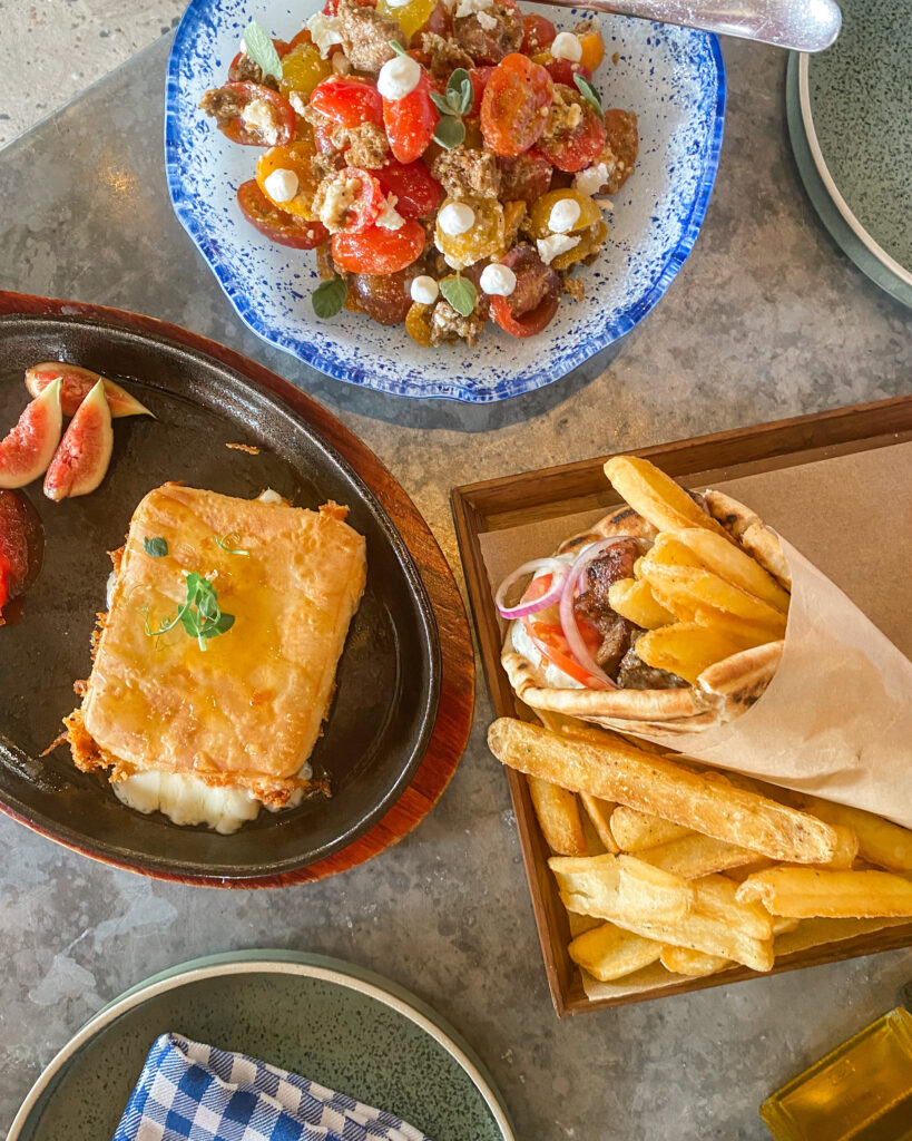 Greek wrap, saganaki and salad on table at Eat Greek Kouzina, Dubai