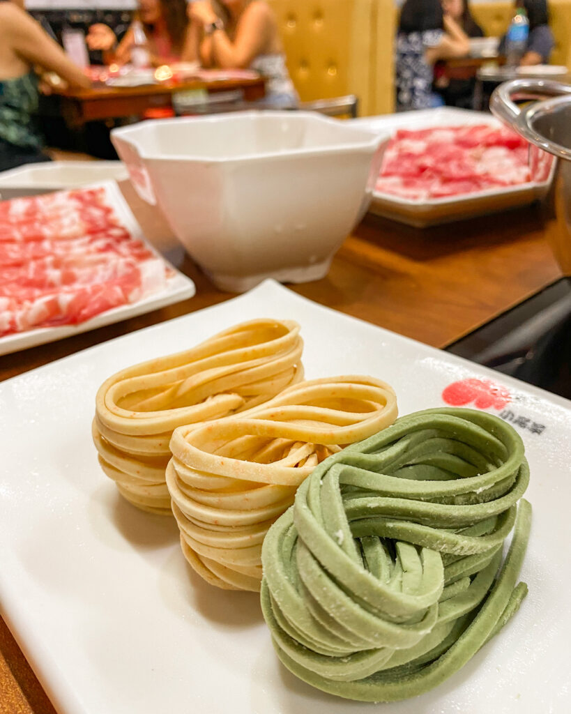 Yellow and green noodles on a plate at Little Lamb Hotpot, Dubai
