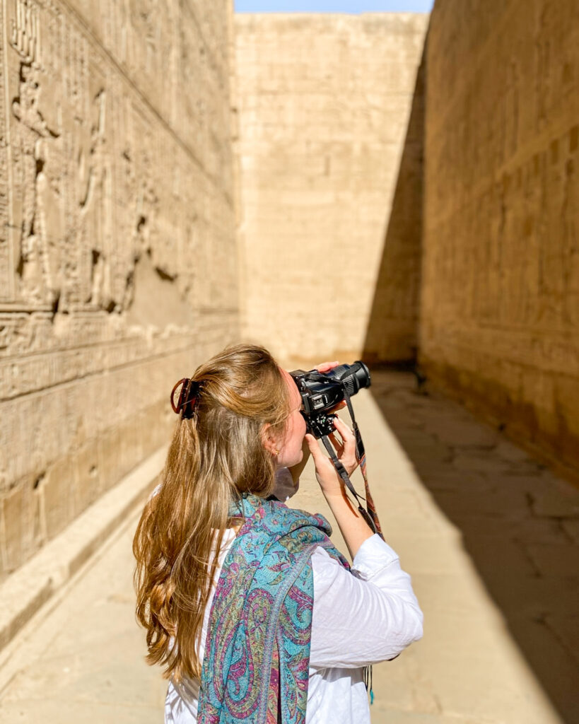 Woman in turquoise patterned scarf photographing Edfu Temple, Egypt