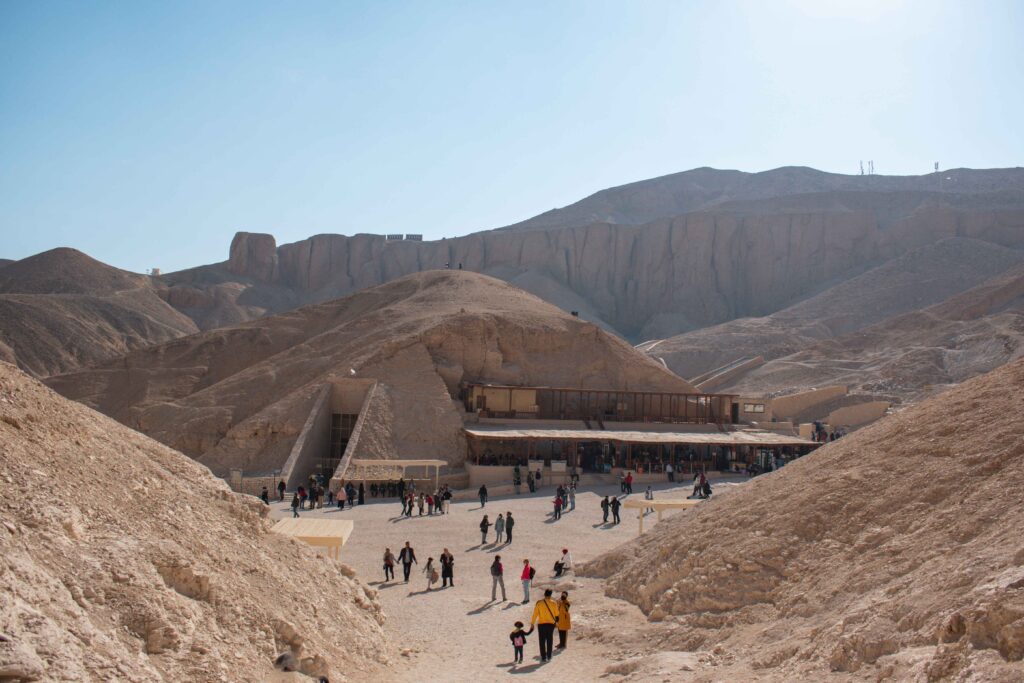 People walking towards the cafe at the Valley of the Kings set amongst the rocky cliffs