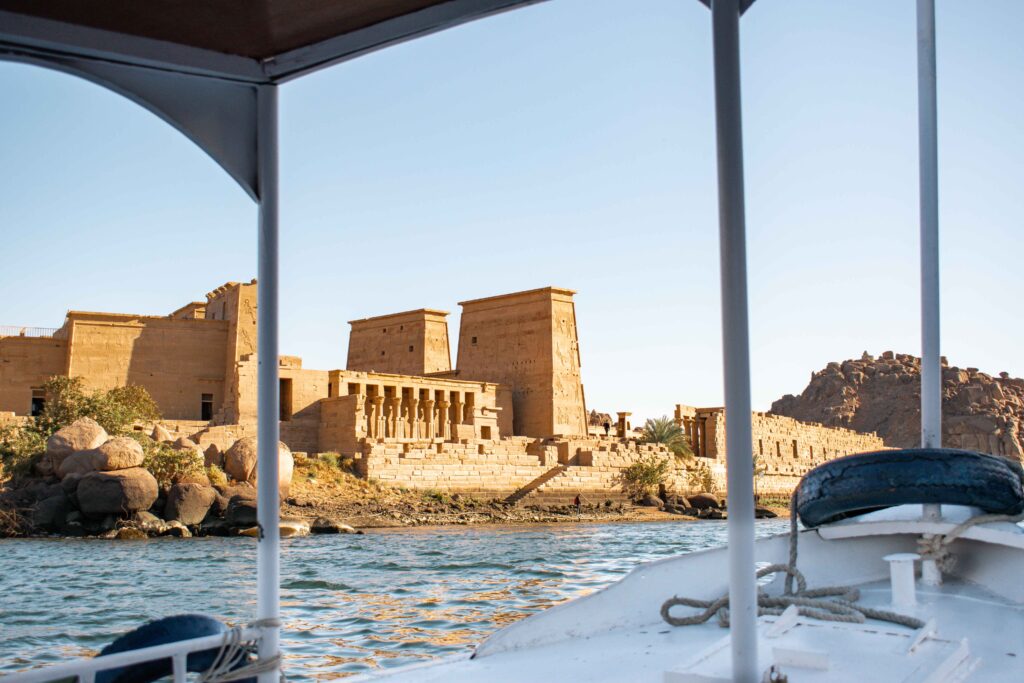 Philae Temple in the afternoon sunlight seen through the bars of a traditional felucca boat. 