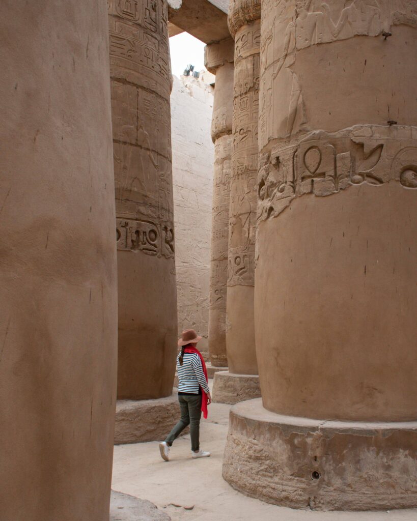 Woman walking between columns at Karnak Temple, Luxor