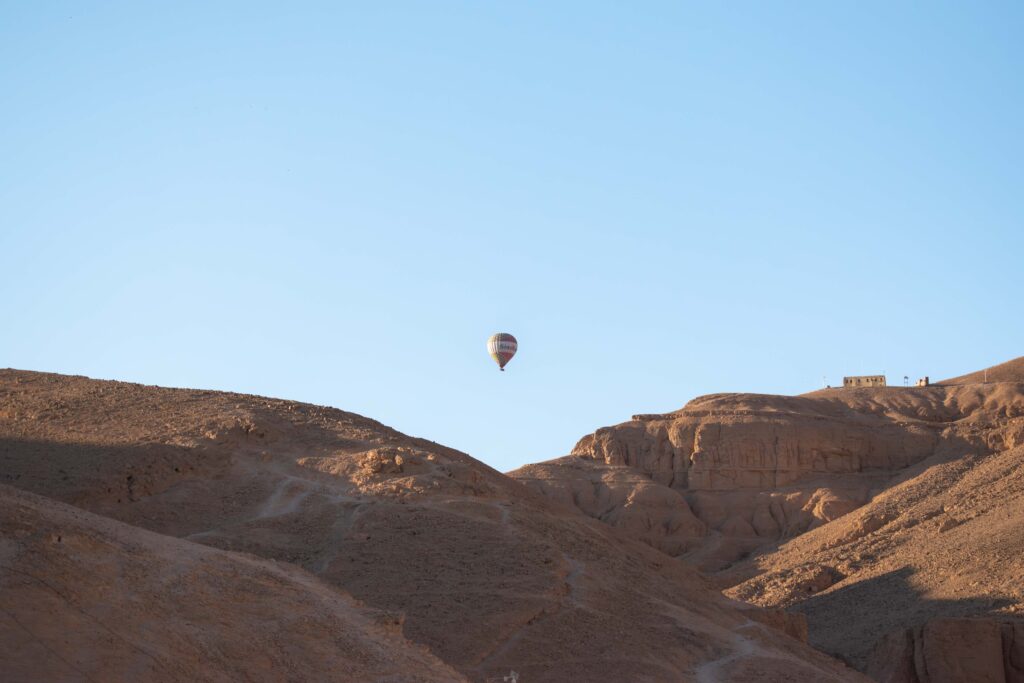 Hot air balloon in the early morning light above the rocky walls of the Valley of the Kings
