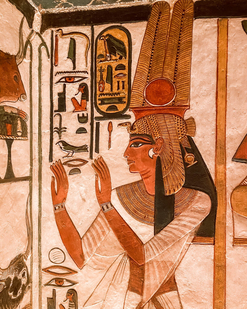 Close detail photo of intricately painted colourful walls covered in hieroglyphs and figures in the tomb of Nefertari