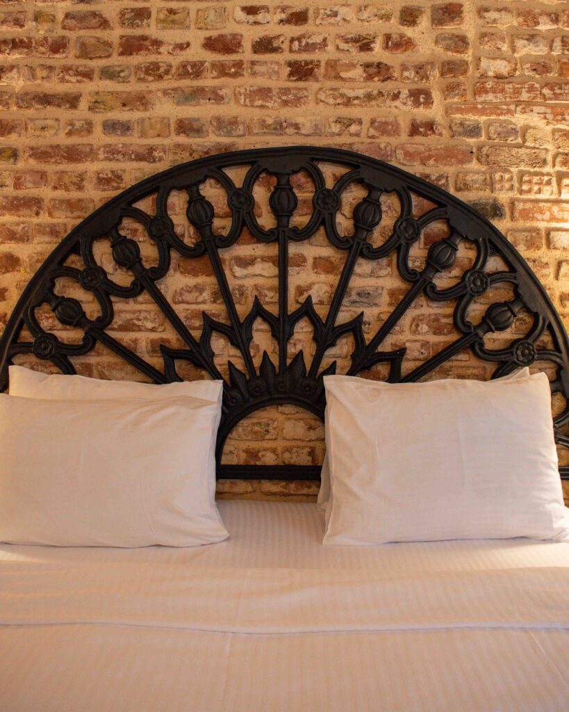 Close up of wrought iron bedhead against a brick wall