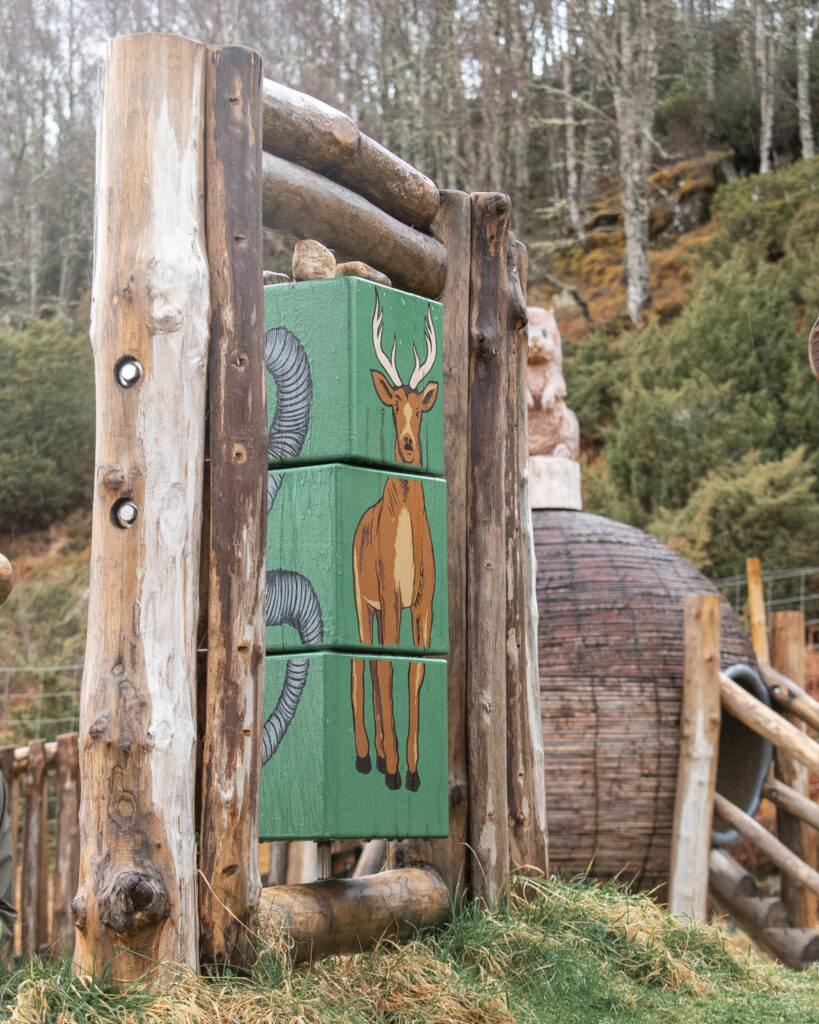 Wooden interactive puzzle featuring a painted deer in the play area at Dundreggan Rewiling Centre in Scotland. 
